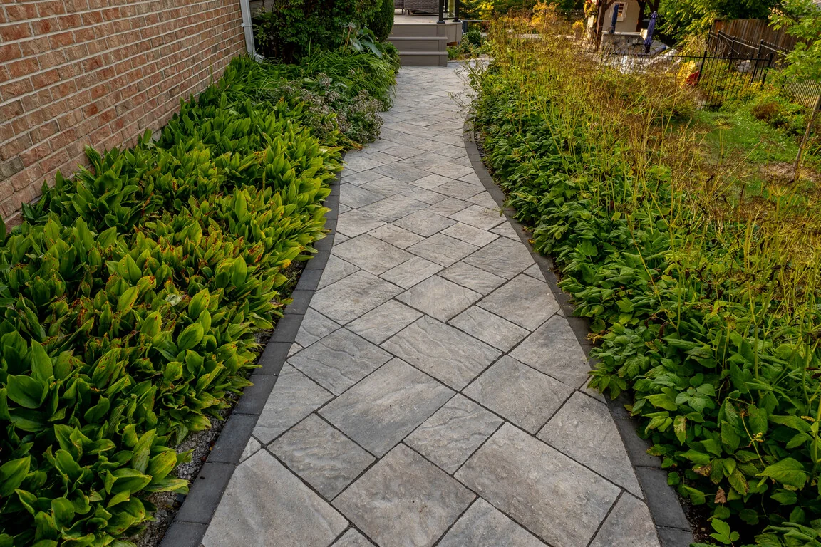 Real Diamond Decks project with an interlocking stone walkway beside planted garden beds