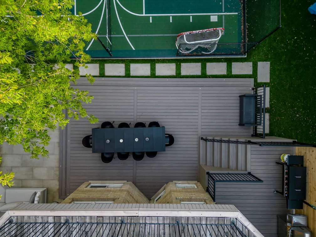 Top-down aerial view of a composite dining deck, stone lounge patio and sport court in a compact North York yard
