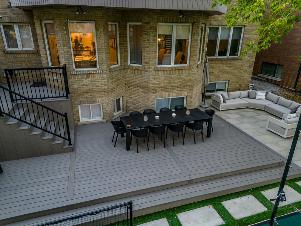 Grey composite deck with picture-frame border, broad steps and outdoor dining furniture in North York
