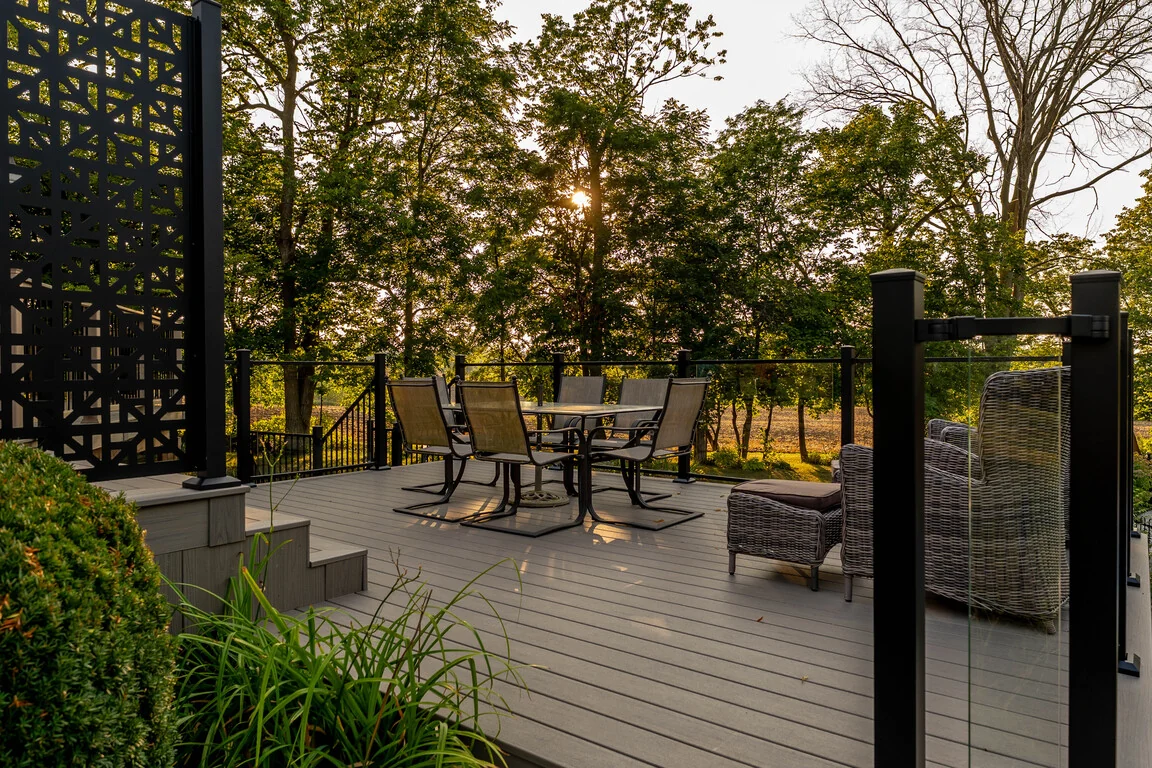 Composite deck dining area with black railing overlooking a wooded Schomberg backyard