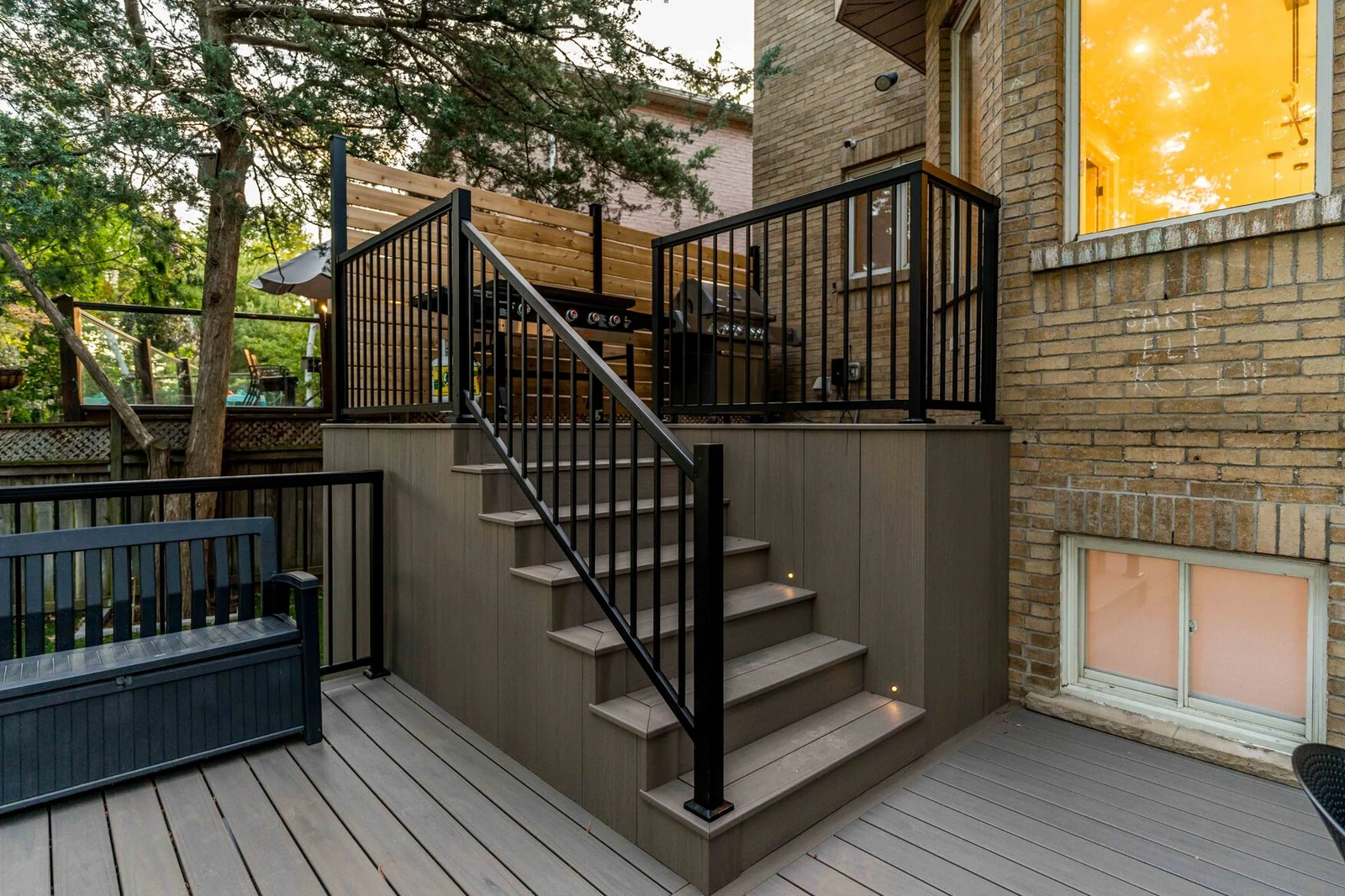 Composite deck stairs with black aluminum railing leading to an upper cooking area in North York