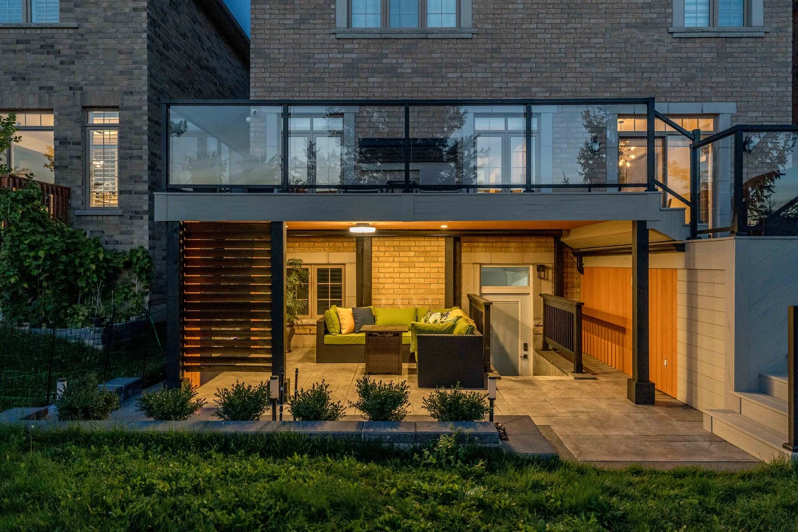 Covered outdoor lounge beneath an elevated composite deck with glass railings in Bradford