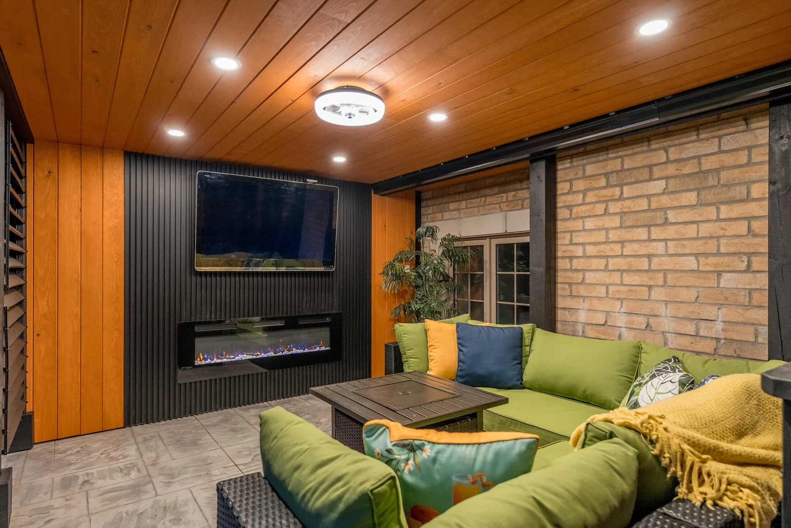 Covered Bradford outdoor lounge with sectional seating, television, electric fireplace and recessed lights