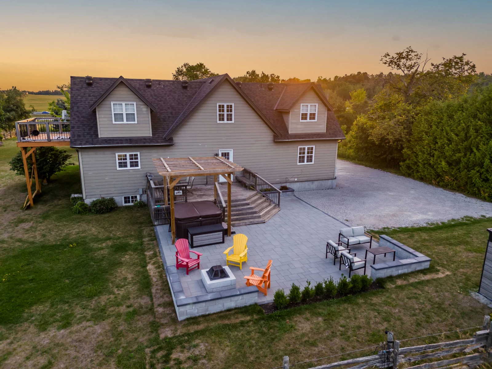 Aerial view of an Innisfil backyard with a hardscape patio, fire pit, lounge, deck, pergola and hot tub