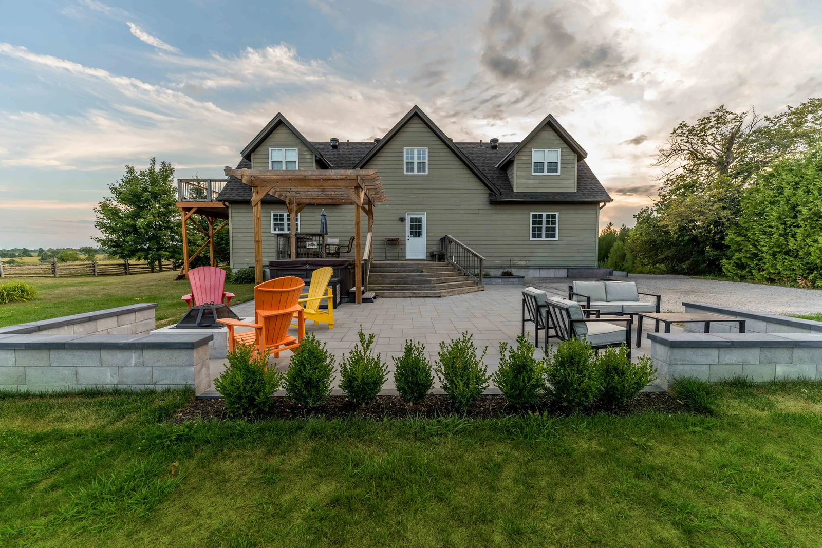 Finished Innisfil hardscape patio with a fire pit, two seating areas and an existing wood pergola