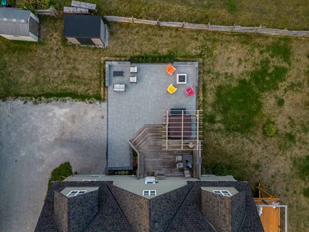 Top-down drone view of an Innisfil patio layout with two seating zones, a fire pit and an existing deck
