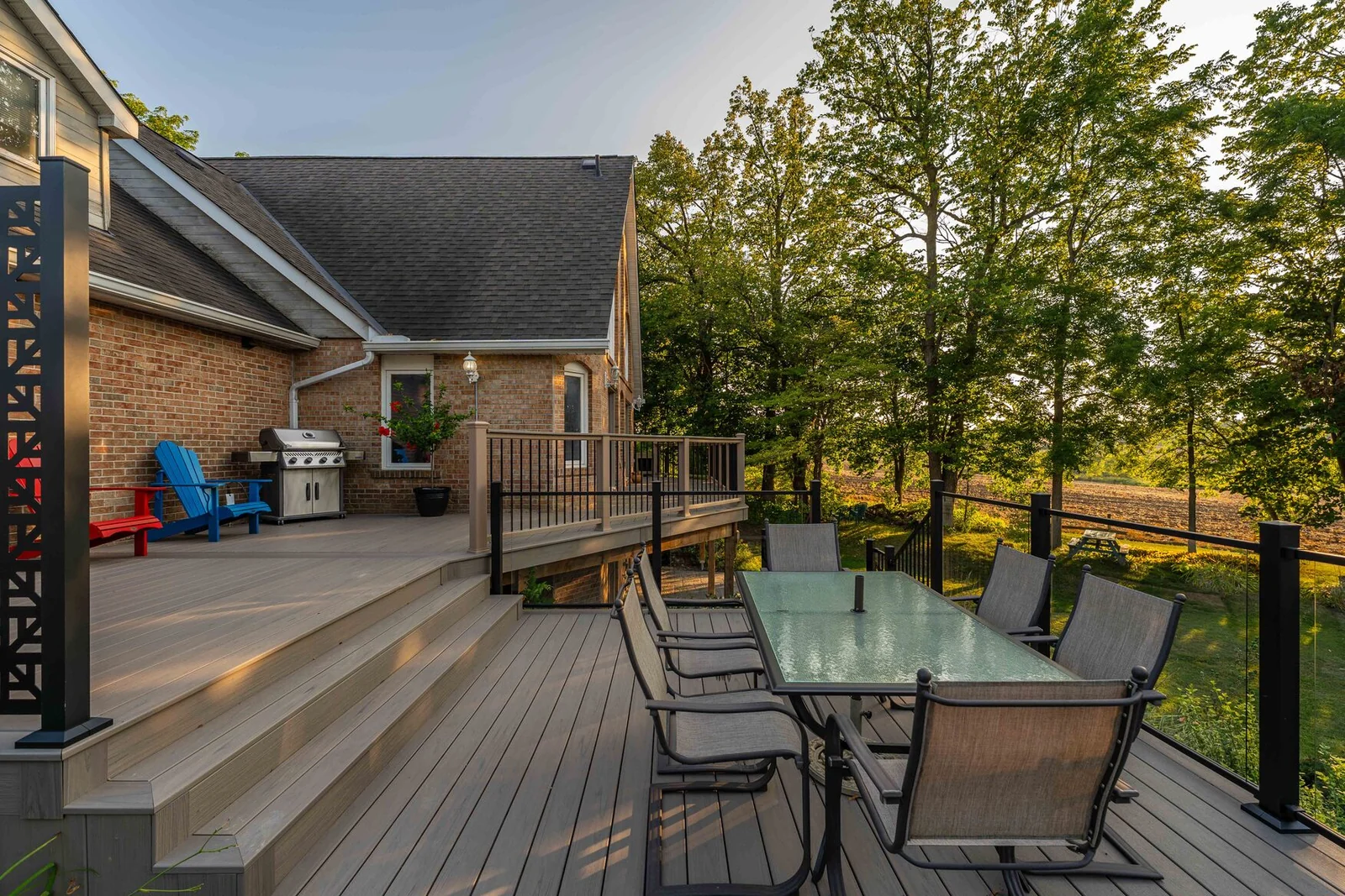 Multi-level composite deck with broad stairs and an outdoor dining area beside a Schomberg brick home