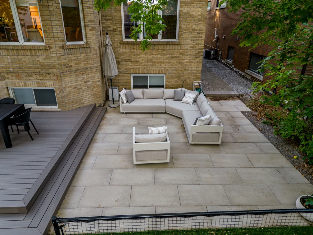 Large-format stone lounge patio beside a grey composite deck at a North York home