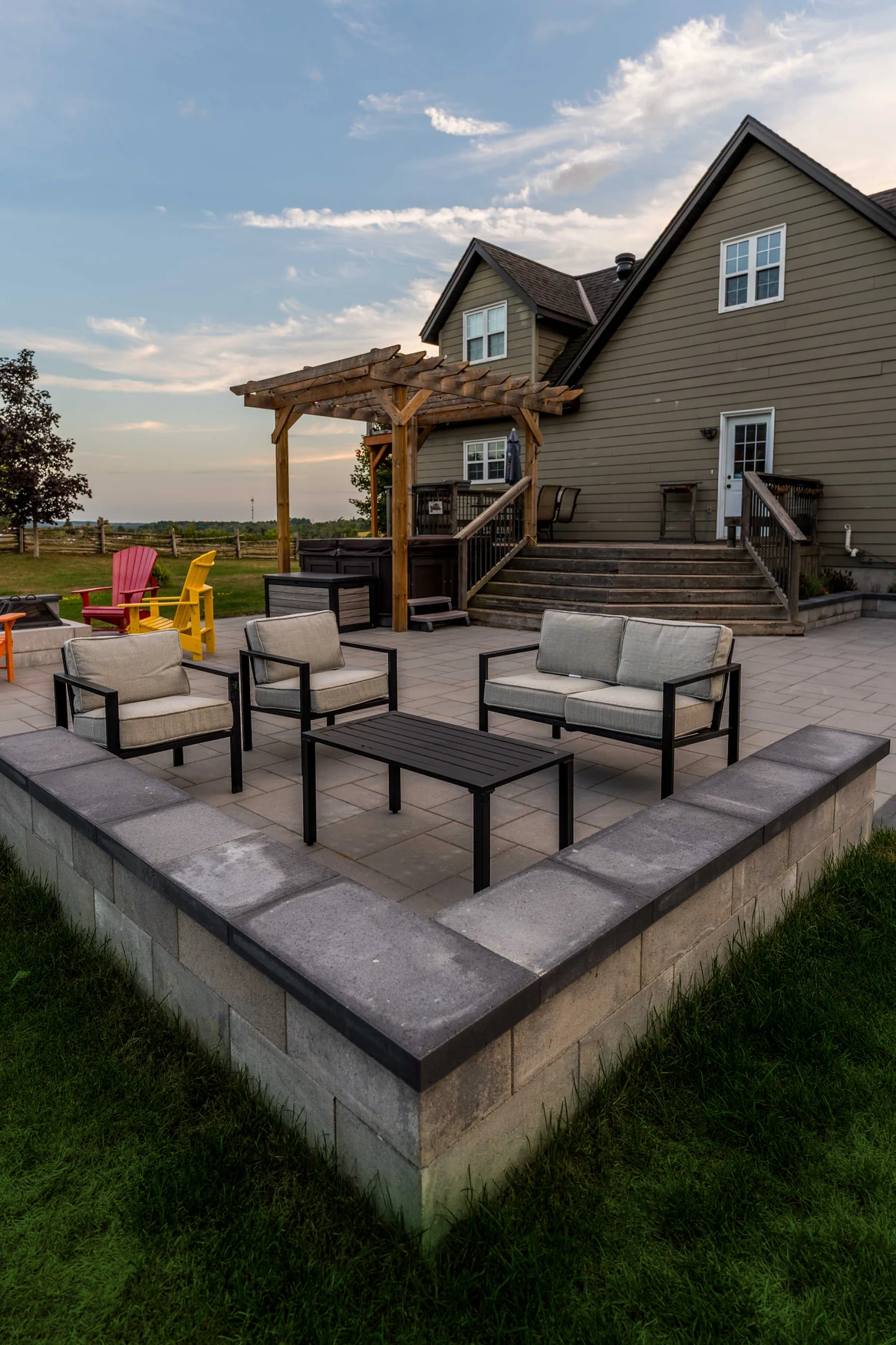 Outdoor lounge framed by low stone retaining walls beside an existing pergola in Innisfil