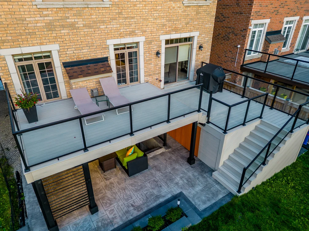 Upper grey composite deck with glass railings, lounge chairs and barbecue at a Bradford home