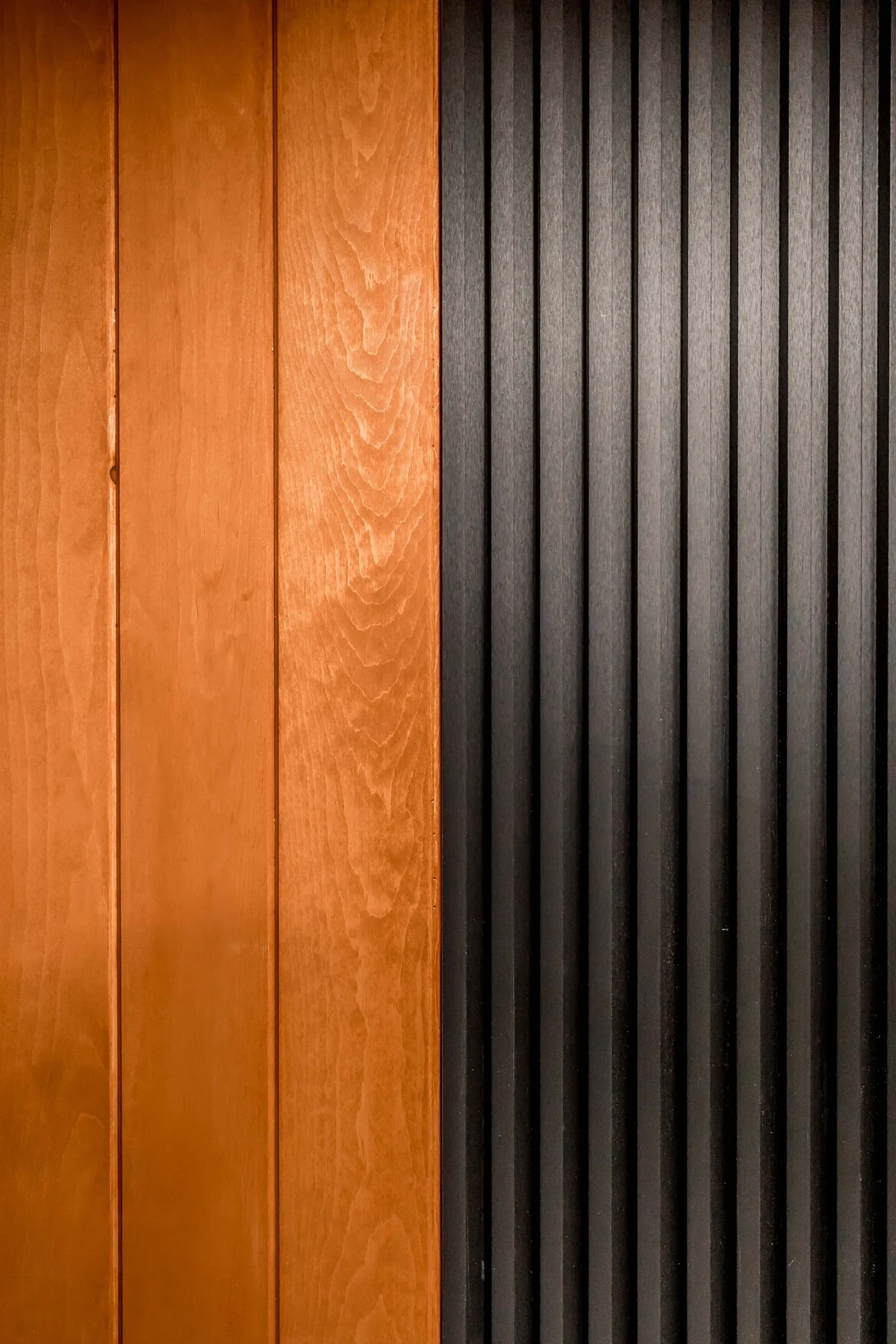 Close detail of warm wood panels meeting a black slatted feature wall in a Bradford outdoor room